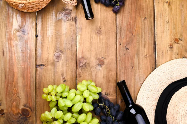 Trauben, eine Flasche Wein, Glas mit Wein, Hut auf einem hölzernen Hintergrund. Weinbereitungs- und Erntekonzept in Europa, Italien. Kopierraum — Stockfoto