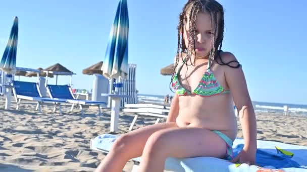 Kleines Mädchen im Badeanzug am Strand spielt, lächelt. Kind 7 Jahre alt am Strand von Italien. Das Konzept eines Sommer-, Familienurlaubs am Meer. Die Person zeigt positive Emotionen. — Stockvideo