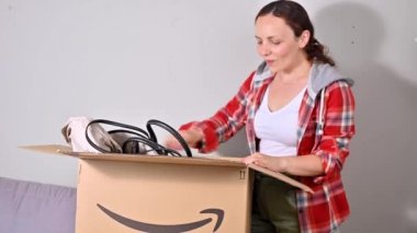 Amazon paketini boşaltıyorum. Bir kadın yaz tatili için şapkasını ve çantasını çıkarır. Başarılı posta, ev ve iş hizmetleri kavramı. Mesaj için yer. 4k görüntü, online alışveriş..