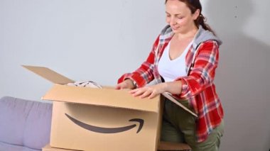 Amazon paketini boşaltıyorum. Bir kadın yaz tatili için şapkasını ve çantasını çıkarır. Başarılı posta, ev ve iş hizmetleri kavramı. Mesaj için yer. 4k görüntü, online alışveriş..