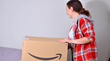 Amazon paketini boşaltıyorum. Bir kadın yaz tatili için şapkasını ve çantasını çıkarır. Başarılı posta, ev ve iş hizmetleri kavramı. Mesaj için yer. 4k görüntü, online alışveriş..