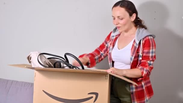 Pakker pakken ud Amazon. En kvinde tager sin hat og taske ud til sommerferie. Begrebet vellykket mailing, service til hjemmet og erhvervslivet. Sted for tekst. 4k optagelser, Online shopping. – Stock-video