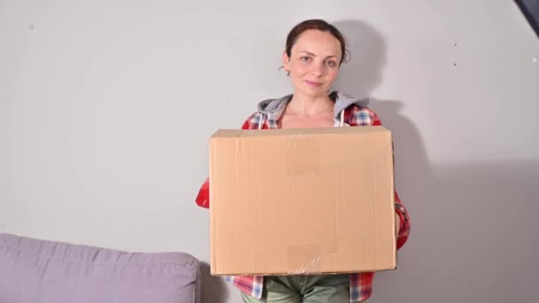 Desempaquetando el paquete. Una mujer sostiene una gran caja de papel en sus manos, un paquete. Concepto de correo exitoso, servicio para el hogar y los negocios. maqueta. Lugar para el texto. Imágenes de 4k, concéntrate en la caja . — Vídeo de stock