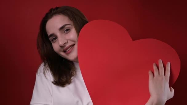 Sevgililer Günü ve Kadınlar Günü konsepti. Elinde kocaman kırmızı bir kalp tutan mutlu bir genç kız. Romantik bir hediye.. — Stok video