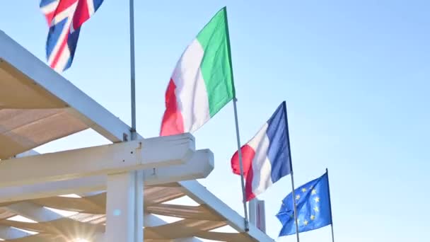 Den italienska flaggan, Europeiska unionen, fransmännen utvecklas mot den blå himlen. Begreppet politiska symboler. — Stockvideo