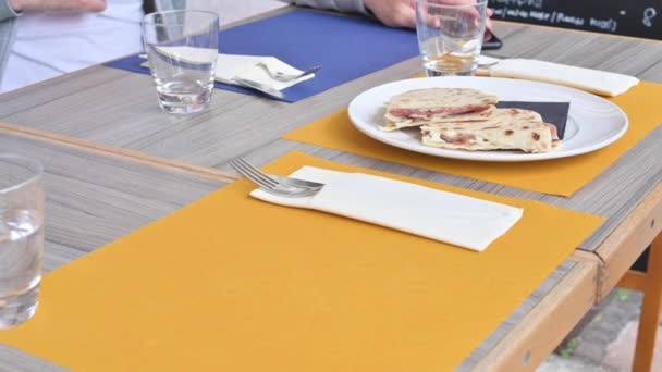 La piadina italiana tradicional de la región de Emilia Rumania, con diversos rellenos. El camarero trajo platos y comida sobre la mesa. Almuerzo en un restaurante italiano. — Vídeos de Stock
