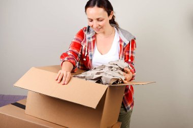 Paketi açıyorum. Kadın kutuyu açıyor ve internetten satın aldıklarını mutlulukla alıyor. Teslimat ve servis konsepti. İnternetten alışveriş. Bu kişi Avrupalı. Metin için boş alan.