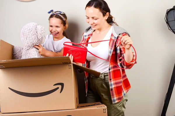 13 Juli 2020 Italia, Bologna. Membongkar paket Amazon. Ibu dan anak membuka kotak dan dengan senang hati mendapatkan pembelian mereka dari toko online. Konsep pengiriman dan pelayanan. Belanja online. Eropa — Stok Foto