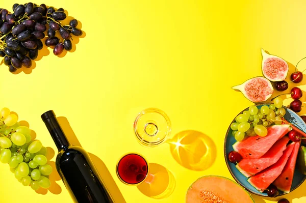 Zwei Gläser Rot- und Weißwein. Eine Frau schenkt Wein aus einer Flasche ein. Trauben und andere Früchte auf gelbem Hintergrund. Das Konzept der Ernte und der italienischen Weinherstellung. — Stockfoto