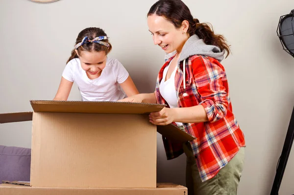 Het pakje uitpakken. Mam en dochter openen de doos en krijgen blij hun aankopen van de online winkel. Levering en service concept. Online winkelen. Europese personen. Vrije ruimte voor tekst. — Stockfoto