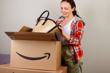 Amazon paketini boşaltıyorum. Bir kadın yaz tatili için şapkasını ve çantasını çıkarır. Başarılı posta, ev ve iş hizmetleri kavramı. Mesaj için yer. 4k görüntü, online alışveriş..