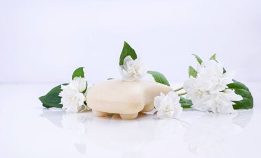 El yapımı yasemin sabunu. Spa ve vücut bakımı için doğal kozmetik ürünleri. Beyaz arka planda sabun ve taze yasemin çiçekleri.