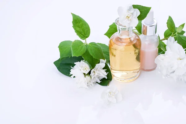 재스민 꽃과 함께 필수적 인 기름과 크림. Aromatherapy 와 대체 의학. 재스민 팅커 싱을 유리병에 넣고 신선 한 꽃봉오리를 많이 심었죠. 부드러운 초점, 밝은 색 사진. 복사 공간 — 스톡 사진