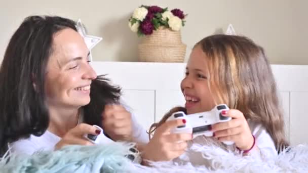 Menina e mãe estão jogando um jogo de computador com a mãe. Jostics na mão. Jogos de computador modernos para crianças e pais. Divulgação de emoções alegres por pessoas. Imagens 4k de alta qualidade — Vídeo de Stock