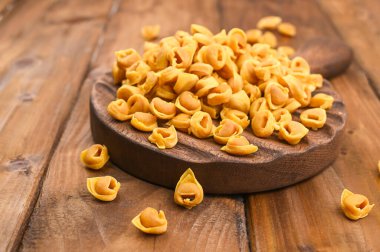 Tahta bir tahta üzerinde Tortellini mignon I ve parmesan. Bologna ve Emilia Romagna mutfağının spesiyaliteleri: Cappelletti, et ve sebzeli taze yumurtalı makarna..