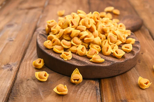 Tahta bir tahta üzerinde Tortellini mignon I ve parmesan. Bologna ve Emilia Romagna mutfağının spesiyaliteleri: Cappelletti, et ve sebzeli taze yumurtalı makarna..