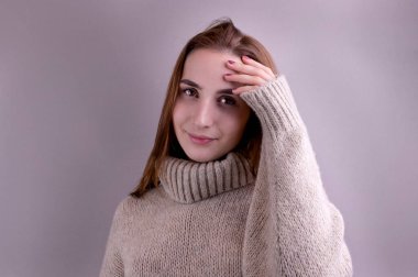 Gri arka planda, kalın kazaklı genç bir kız. Kış kıyafetleri içinde Avrupalı bir insan. Metin için boş alan.