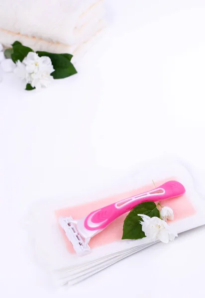 Um grupo de meios diferentes do epilation em um contexto colorido. Remoção de pêlos indesejados. Produtos de cuidados com o corpo, toalhas, flores de jasmim, tiras de cera, navalha. Minimalismo, vista de cima. flatlay. — Fotografia de Stock