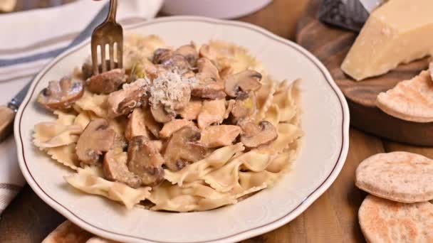 Вилка в тарелке с макаронами. Паста-бабочка с грибами и соусом из сыра пармезан. Типичная итальянская кухня с юга Италии. — стоковое видео