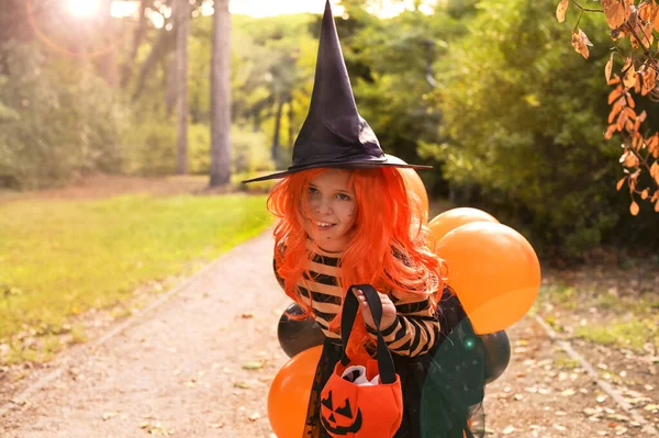 Niña alegre vestida de bruja con canasta de dulces —  Fotos de Stock