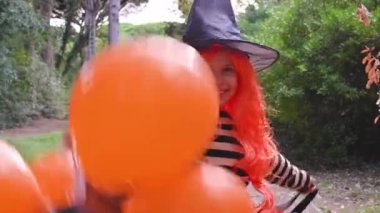 Cadılar Bayramı 'nda büyük renkli balonlarla karnaval kostümü giymiş bir çocuk. Sonbahar parkındaki küçük kız. Ana nesneye odaklanmak kolay..