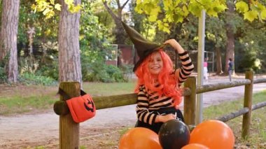 Cadılar Bayramı 'nda büyük renkli balonlarla karnaval kostümü giymiş bir çocuk. Sonbahar parkındaki küçük kız. Ana nesneye odaklanmak kolay..