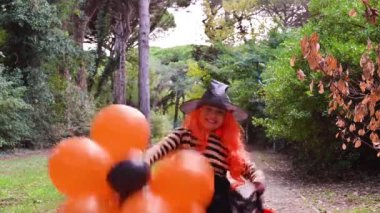 Cadılar Bayramı 'nda büyük renkli balonlarla karnaval kostümü giymiş bir çocuk. Sonbahar parkındaki küçük kız. Ana nesneye odaklanmak kolay..