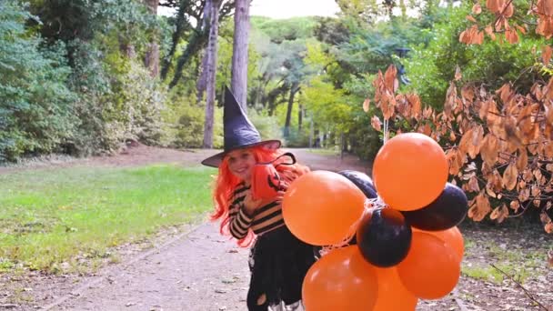 Un bambino in costume da carnevale ad Halloween con grandi palloncini colorati. Bambina nel parco autunnale. Il focus è morbido spostato sull'oggetto principale. — Video Stock