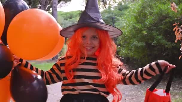 Un bambino in costume da carnevale ad Halloween con grandi palloncini colorati. Bambina nel parco autunnale. Il focus è morbido spostato sull'oggetto principale. — Video Stock