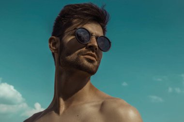 Güçlü ticari yüz erkek model mavi gökyüzü arka plan üzerinde gözlük takıyor