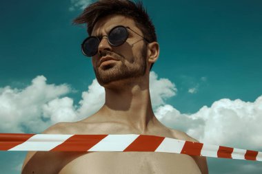 Güçlü ticari yüz erkek model mavi gökyüzü arka plan üzerinde gözlük takıyor