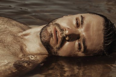 Seksi güçlü sakallı erkek yakışıklı yaz vibes ile su arka plan üzerinde kırmızı yüzmek şortlu