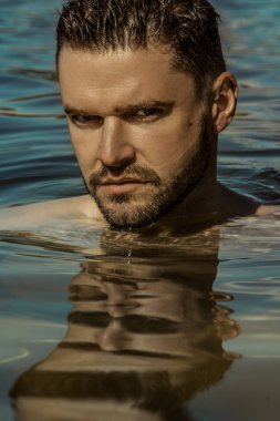 Seksi güçlü sakallı erkek yakışıklı yaz vibes ile su arka plan üzerinde kırmızı yüzmek şortlu