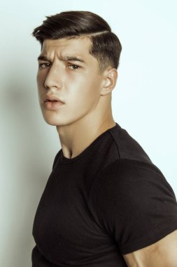 Kas gücü, siyah tişörtlü ve siyah iç çamaşırlı güzel erkek model, gri izole yazı tipi arka planda.