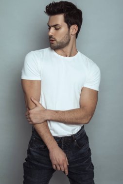 Kas gücü, kot pantolonlu, gri izole font arka planda beyaz tişörtlü güzel erkek manken.