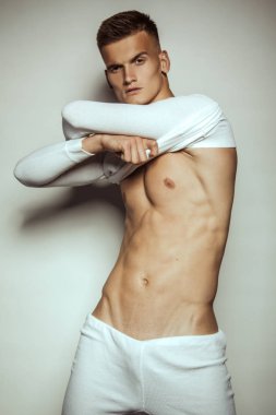 Yakışıklı seksi erkek portresi. İzole edilmiş arka planda beyaz spor giysisi var.