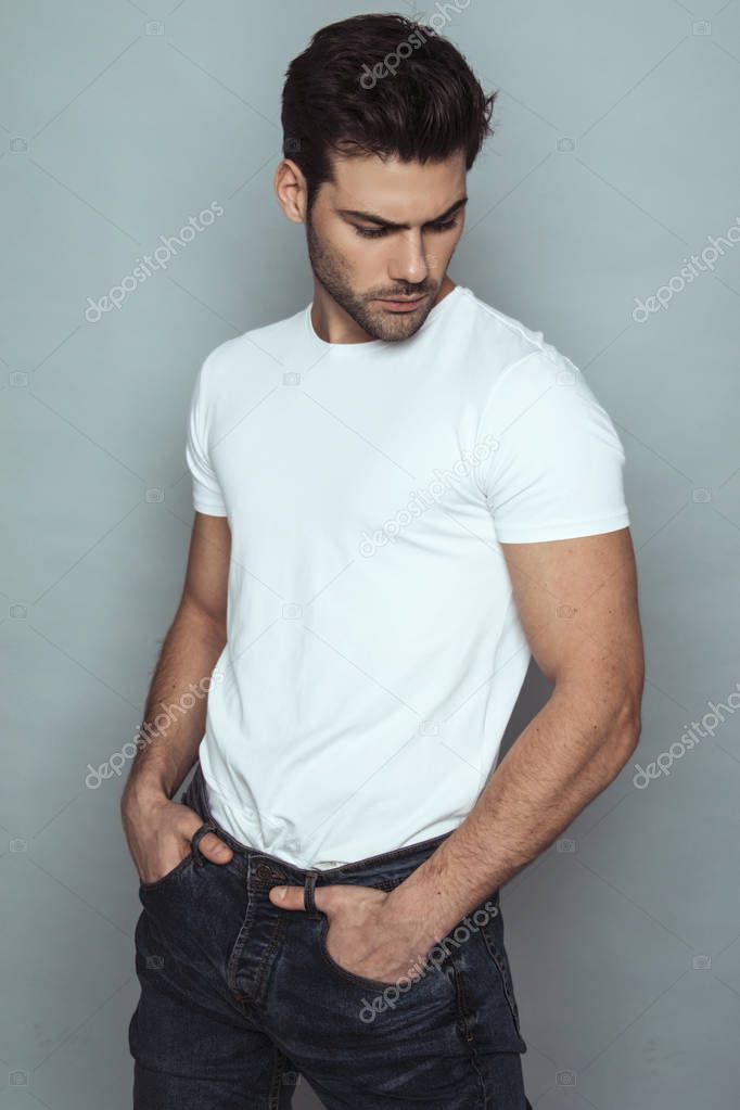 Muscle strong beautiful stripped male model in denim jeans with white t-shirt on grey isolated font background