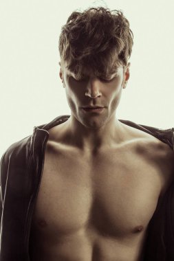 Siyah deri ceketli, beyaz izole yazı tipi arka planda güçlü, kaslı bir erkek model.