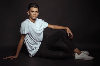 Beyaz tişörtlü, siyah pantolonlu ve siyah izole yazı tipli güçlü erkek modeller.