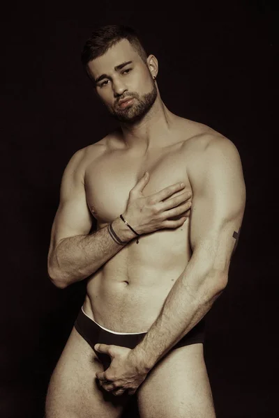 Muscle strong bearded face beautiful stripped male model in black underwear on black isolated font background