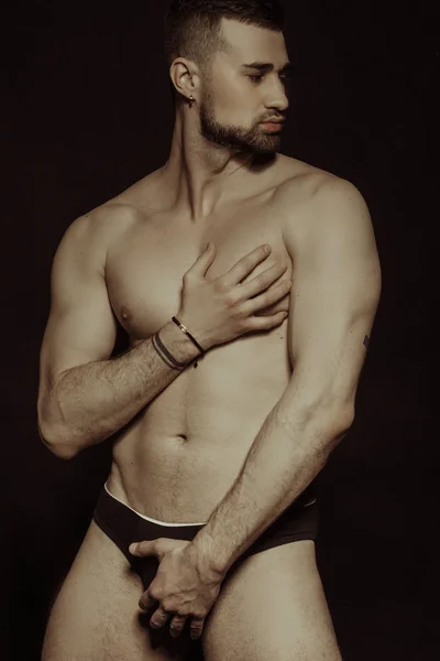 Muscle strong bearded face beautiful stripped male model in black underwear on black isolated font background