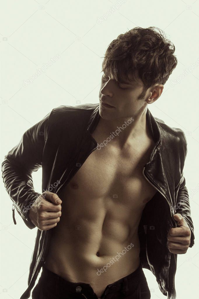 Strong stripped muscle male model in casual look in black leather jacket on white isolated font background