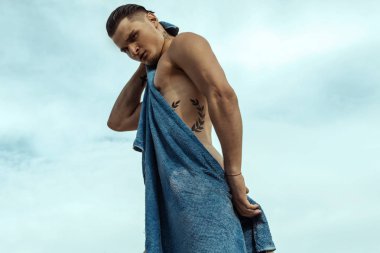 Gün batımında sahilde kum ve su ve gökyüzü ile doğa arka planda güçlü yüz erkek modeli