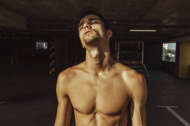 Kentsel park arka plan üzerinde denim mavi kot pantolon ve siyah deri ceket Kas yakışıklı sıyrılmış erkek modeli