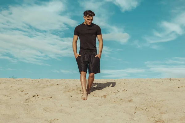 Strong face male model on the nature background with sand and water and sky on the beach on the sunset