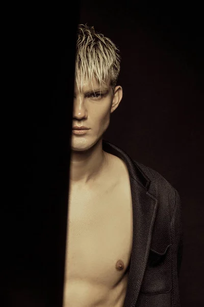 Handsome stripped blonde male model wearing black suit on black isolated font background