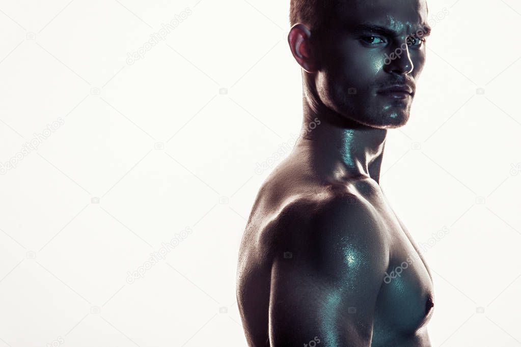 Sport sexy stripped muscle guy portrait in colored light on shine isolated white font background