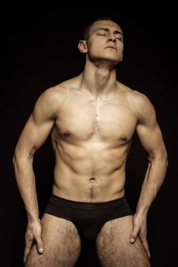 Yakışıklı seksi erkek portresi. Günlük giysiler ve iç çamaşırlarıyla su damlaları ve izole edilmiş siyah arka plan.