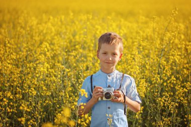 Küçük çocuk fotoğrafçı günbatımı sarı alan arka plan üzerinde kamera ile portresi.