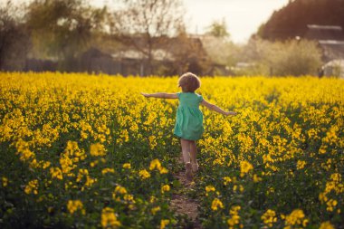 Küçük çocuk runing güneşli yaz gün sarı zemin üzerinde. Arkadan görünüm